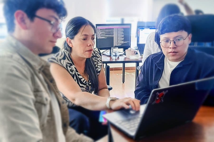 Ingenieros de Senirop revisando código juntos en una laptop en la oficina de Quito