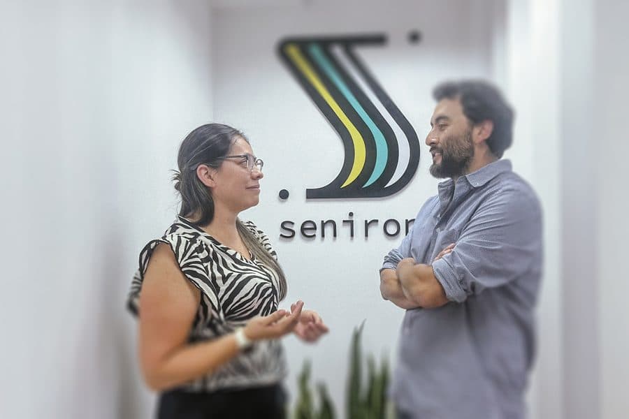 Dos colegas de Senirop conversando frente al muro del logo en Quito