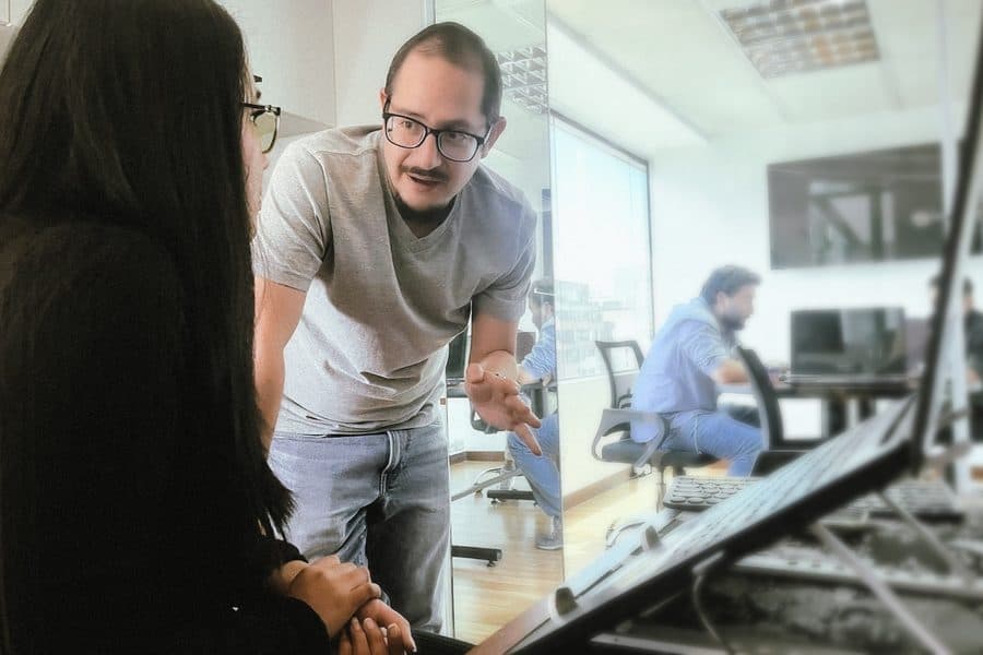 Una consultora de Senirop explicando una solución técnica a un colega en su estación de trabajo