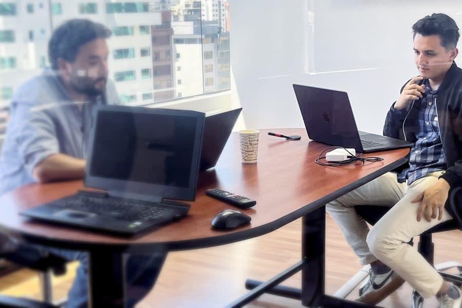 Dos ingenieros de Senirop trabajando desde la sala de reuniones de la oficina de Quito, con el horizonte al fondo