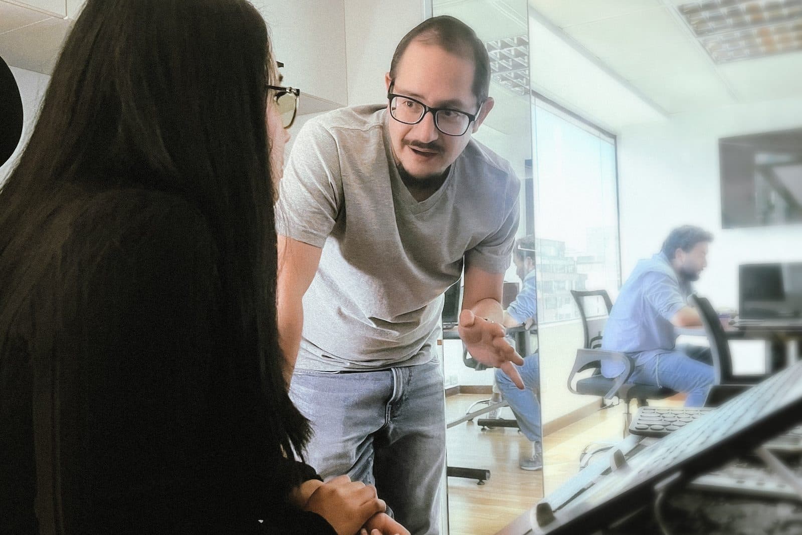 A senior Senirop engineer talking a colleague through a solution at her workstation on the Quito, Ecuador engineering floor