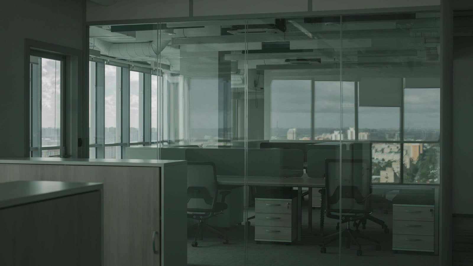 Un espacio de oficina de planta abierta detrás de divisiones de vidrio, con vista al horizonte de la ciudad