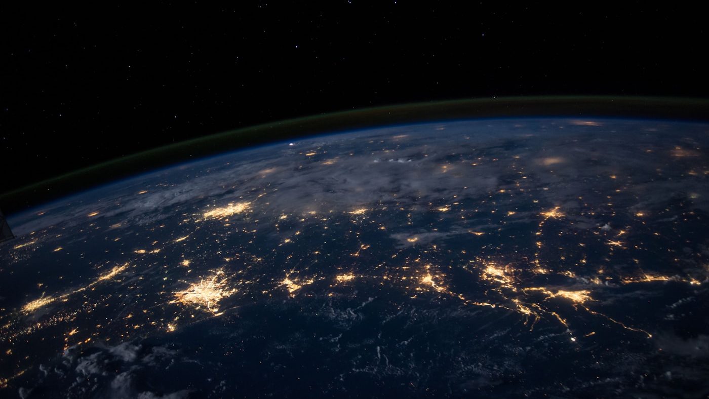 City lights spread across the Earth at night, photographed from orbit.